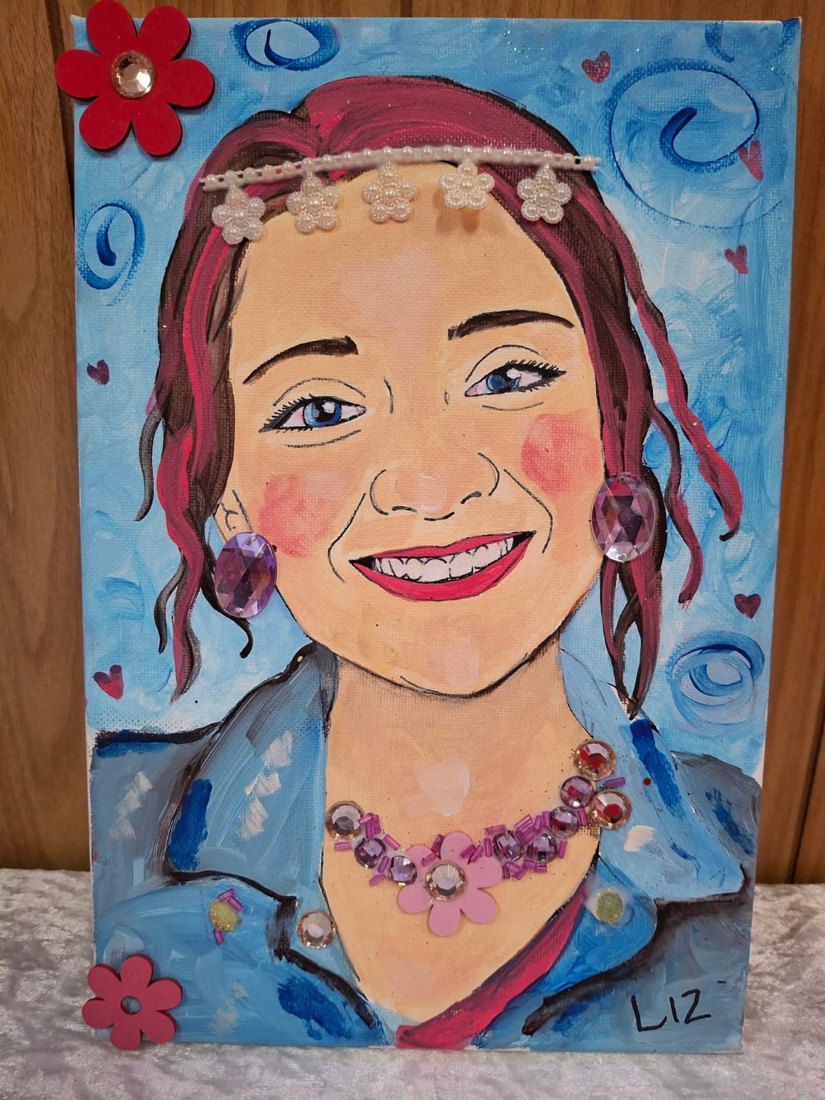 An adult's expressive self-portrait with painted detail, beads, gems and flowers, made at a Canvas Hope workshop